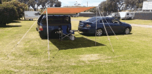 a blue car is parked under a canopy in a field