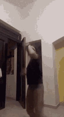 a woman is dancing in a hallway with a door open .