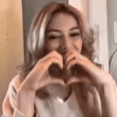 a young woman is making a heart shape with her hands .