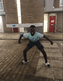 a young boy is standing on a brick sidewalk with his arms outstretched