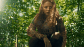 a woman in a leopard print sweater is standing in the woods