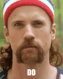 a man with a beard wearing a red white and blue headband has the word do written on his neck