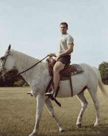 a man riding a white horse in a field with a t-shirt that says ' texas ' on it