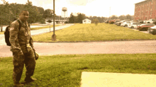 a man in a military uniform stands in front of a parking lot with a water tower in the background