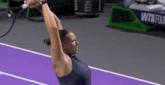 a woman holding a tennis racquet on a purple court