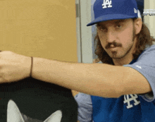 a man wearing a la dodgers hat holds a cat