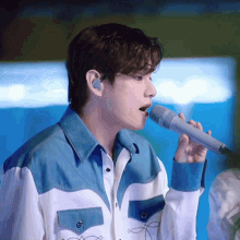 a man singing into a microphone with a blue and white shirt on