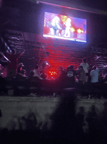 a group of people are watching a concert with a large screen behind them