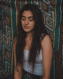 a woman with her eyes closed sitting in front of a colorful rug