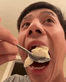 a man is eating a piece of food with a spoon in his mouth .