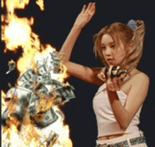 a woman is holding scissors in front of a pile of money that is on fire