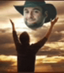 a man in a cowboy hat is standing in front of a sunset with his arms in the air .