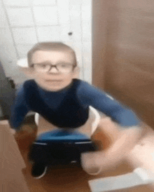 a young boy with glasses is sitting on a potty .