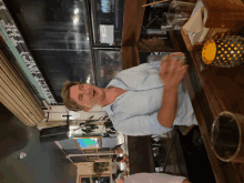 a man in a blue shirt is standing at a bar with a sign that says ' a ' on it