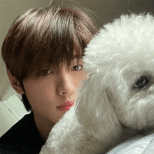 a young man laying on a bed with a white fluffy dog