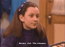 a young girl wearing a headband and a purple turtleneck is saying `` becky , cut the cheese . ''