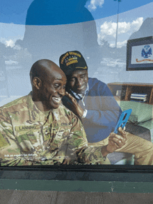 a man in a u.s. army uniform looks at a cell phone