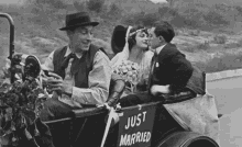 a black and white photo of a bride and groom kissing in a car with a sign that says just married