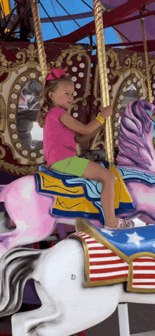 a little girl is riding a pink carousel horse