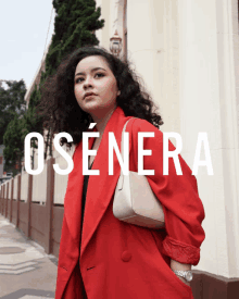 a woman in a red coat is standing in front of a building with the word osenera on it