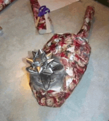 a cat wrapped in christmas wrapping paper with a bow on top