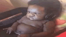 a baby wearing headphones is sitting on a couch .