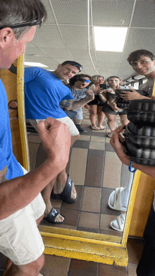 a man taking a picture of a group of people in a mirror