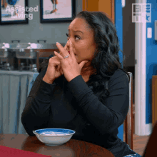 a woman sits at a table with a bowl of food and a sign that says assisted living on it