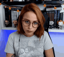 a woman wearing glasses stands in front of a shelf with books including one titled ' a certain magic ' on it