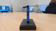 a blue object sits on a wooden table in front of a group of people