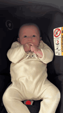 a baby in a car seat with a warning sticker on it