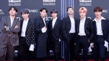 a group of men standing on a red carpet in front of a billboard sign