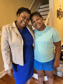 a woman in a blue dress and a girl in a blue shirt are posing for a photo