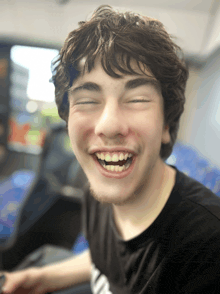 a young man is smiling with his eyes closed and his teeth showing