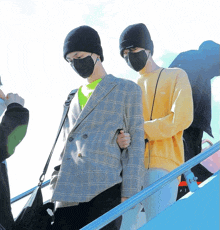 two men wearing face masks are walking down stairs together