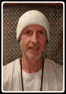 a man with a beard wearing a white beanie and a necklace