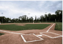 a baseball field with a few trees in the background and a few lights on