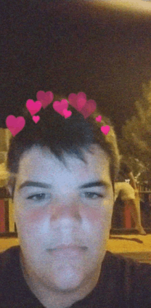 a young man with pink hearts on his head looks at the camera