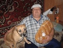 a man holding a loaf of bread and a dog looking at the camera