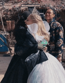 a woman in a white dress hugs another woman in a black dress