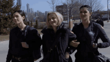 three female firefighters are walking down a sidewalk and one of them is wearing a jacket that says chicago fire department