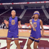 two women are dancing on a basketball court wearing purple jerseys that say ' ucsd ' on them