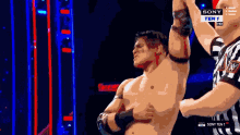 a shirtless wrestler is being held up by a referee on sony ten 1