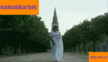 a woman in a white dress is dancing in front of a church with the word namaskaram on the top