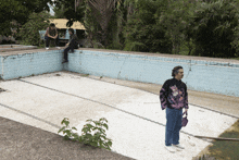 a man stands in front of an empty swimming pool with a sign that says " no swimming " on it