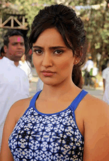 a woman in a blue and white dress is standing in front of a group of people .