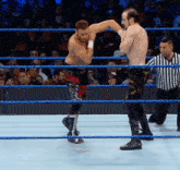 two men are wrestling in a ring with a referee in the corner