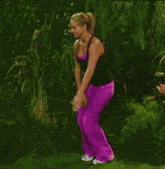 a woman in purple pants is standing next to another woman in a black tank top