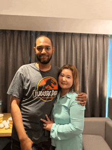 a man wearing a jurassic park shirt poses for a picture