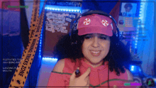 a woman wearing headphones and a pink hat is smiling in front of a warning tape that says " festivities today "